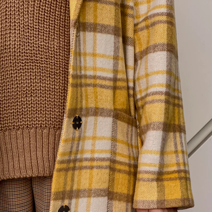 Layered knitwear and yellow plaid jacket detail